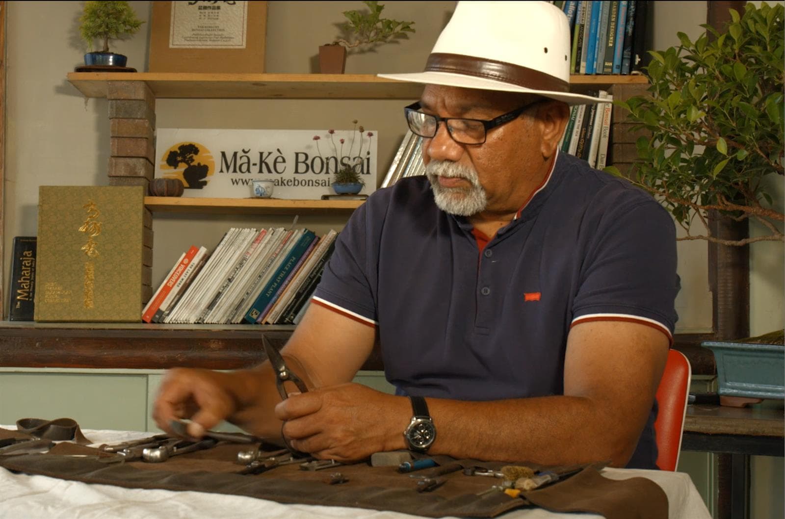 Instructor demonstrating bonsai tool care at a workbench